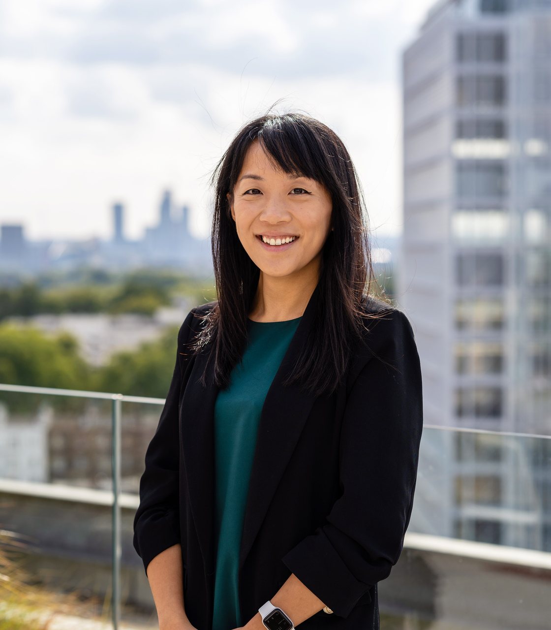 Fei Wang, smiling, on a rooftop terrace with the London skyline behind her